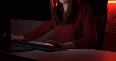 为球员玩家年轻的亚洲女人玩在线视频游戏拍摄帧/秒比赛排名网络互联网晚上红色的霓虹灯光房间游戏耳机键盘冠军事件